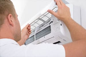 A Comfort Solutions expert inspecting an air conditioning unit in a home on the Sunshine Coast