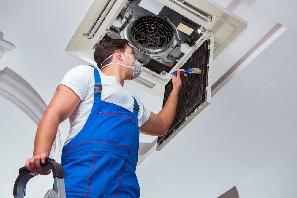 Man Cleaning Air Conditioner Above — Air Conditioning In Sunshine Coast,QLD